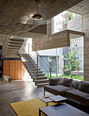 Seating area on the ground floor, staircase to mezzanine in a concrete house