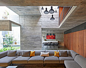 Open living room with sofa set and wooden fixtures in a concrete house