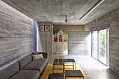 Sofa with table set in seating area with terrace access in concrete house