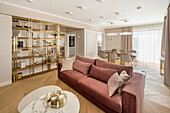Upholstered sofa, brass shelves, and dining area in elegant living room in pastel shades