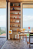 Dining area with retro table and built-in shelves with a view of the sea