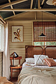 Double bed with rattan headboard in the guest room in earthy colors
