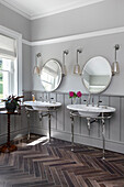 Two unique marble washbasins with round mirrors above them