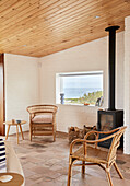 Lounge mit Rattanmöbeln, Kaminofen und Blick auf das Meer