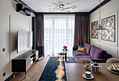 Dark purple sofa, round coffee tables, wall decor with tropical pattern wallpaper and TV corner