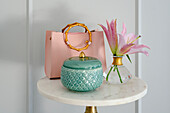 Small table with pink handbag, lily and turquoise earthenware box with lid