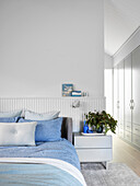 Helles Schlafzimmer mit blauer Bettwäsche und Einbauschränken