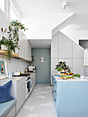 Open-plan white kitchen with high ceilings and blue colour accents