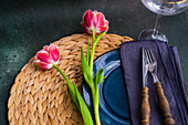 Place setting with sea grass place mat, blue ceramic plate, and tulips (Tulipa)