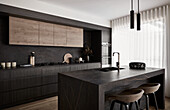 Modern, dark-toned kitchen with marble kitchen island
