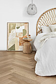 Bright bedroom with cane headboard, oak parquet flooring, and bedside table