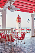 Hotelbar auf der Terrasse, im Hintergrund Leuchtturm am Meer