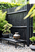 Modern gestalteter Gartenbereich mit schwarzer Holzwand und Dekorelementen