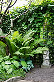 Löwenskulptur umgeben von üppigem Grün in einem Garten