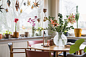 Bright dining area with flower arrangement and window decorations made of stars
