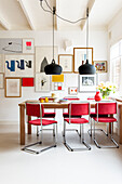 Dining area with table, red chairs and picture wall