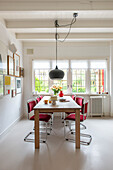 Bright dining area with red chairs and pendant light