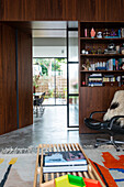 Living room with bookshelf, patterned rug and chair with fur, view of dining area and terrace