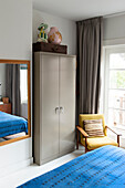 Bedroom with mirror, retro armchair, wardrobe and blue bedspread