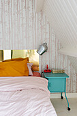 Bedroom with sloping ceiling and bedside table in turquoise