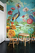 Colourful wall design with flora and fauna, rattan furniture and a dark wooden floor