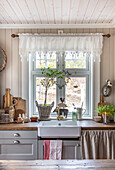 Landhausküche mit Spülbecken unter Fenster und rustikaler Dekoration