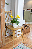 Yellow flowers in a white vase on a wooden chair