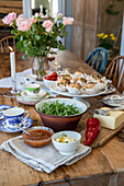 Rustikal gedeckter Esstisch mit Blumenstrauß und hausgemachten Speisen