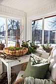 Entrance hall with table, woven basket, armchair and plants on a white windowsill