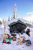 Winterliche Gartenhütte mit Feuerstelle und Fellen im Schnee