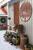 Terrasse mit Winterdeko, Rostelementen und Pflanzen im Schnee