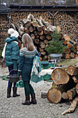 Zwei Frauen in Winterkleidung vor Holzstapeln