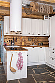 Country kitchen with white cupboards and rustic wooden backsplash