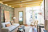 Living room with patterned wallpaper, ceiling beams and vintage decor