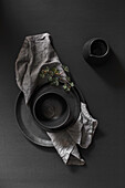 Black ceramic plate, bowl, and jug on black background
