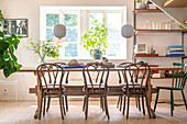 Rustic dining table with wooden chairs and pendant lights in front of window