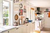 Bright kitchen with white cupboards and wall decorations