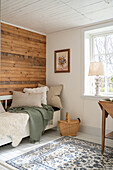 Day bed, woollen blankets, patterned carpet and wood panelling