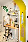 Small kitchen with yellow accent wall, wooden table and shelves