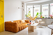 Bright living room with yellow door and brown sofa