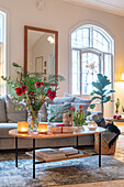 Living room with red amaryllis and tulips on coffee table, candles and mirror