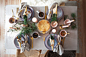 Festive table setting with gold-coloured cutlery and fir branches