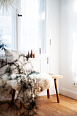 Wooden bench with pillow and fur in front of window