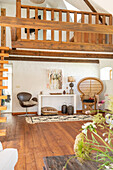 Cosy living room with gallery, wooden floor and rattan armchair