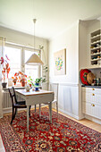 Dining area with oriental carpet, pendant light and plants