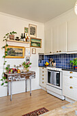 Kitchen with vintage wooden table, white cupboards and blue wall tiles