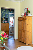 Vintage wooden cupboards, yellow walls, floral wallpaper, view into the bedroom