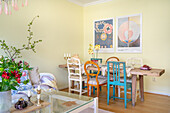 Colourful dining area with different chairs and wall art