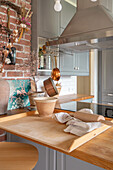 Kitchen work area with wooden counter, pots and brick wall