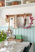 Wooden hook rail with decoration, dining table with tablecloth and bouquet of flowers